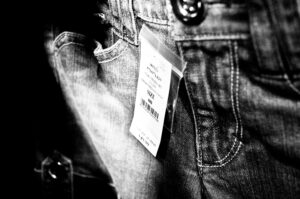 A black and white photograph of a pair of jeans with the tag on