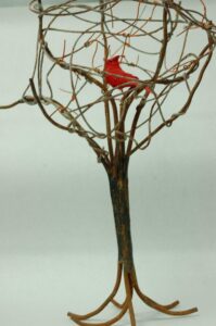 A metal rusted sculpture of a tree with a red bird in the center